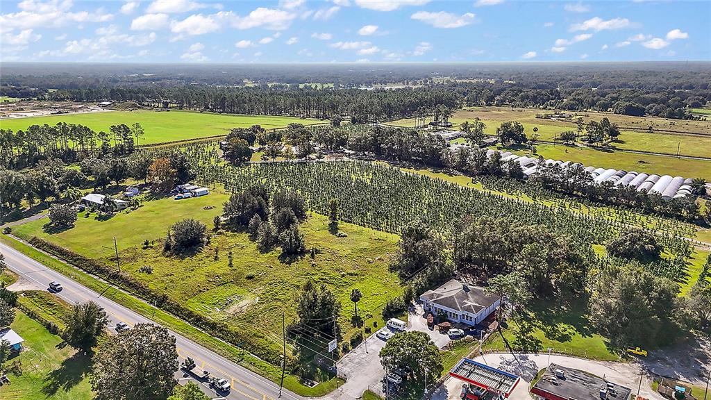 An aerial view shows a commercial building, a gas station, and a large agricultural field — SR-44, SORRENTO, FL