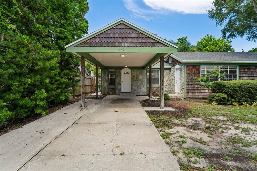 A single-story house with a shingled exterior, stone facade, and a covered carport entrance — 14623 SUNSET DRIVE, LARGO, FL
