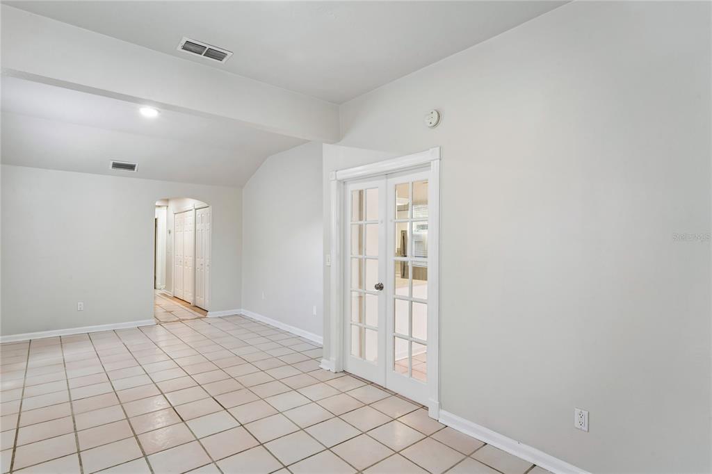 A room with light-colored tile flooring, white walls, and white French doors — 14623 SUNSET DRIVE, LARGO, FL