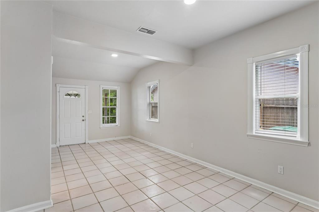 An empty room features light-colored tile flooring, white walls, and three windows — 14623 SUNSET DRIVE, LARGO, FL