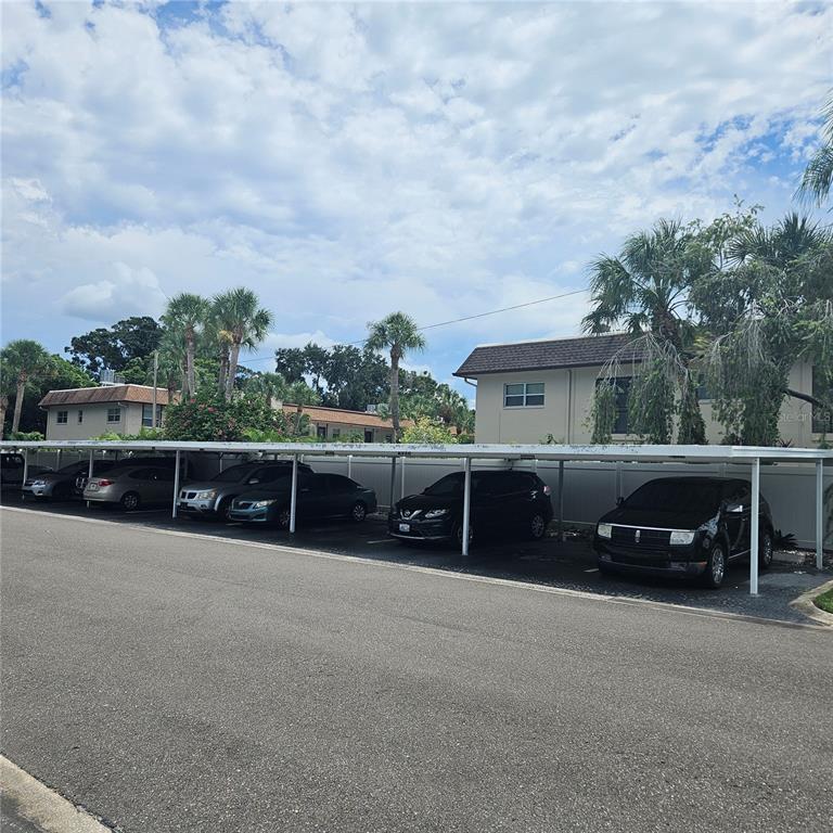 A parking lot features covered carports in front of multi-story apartment buildings with palm trees — 802 BRANDY WINE DRIVE, LARGO, FL