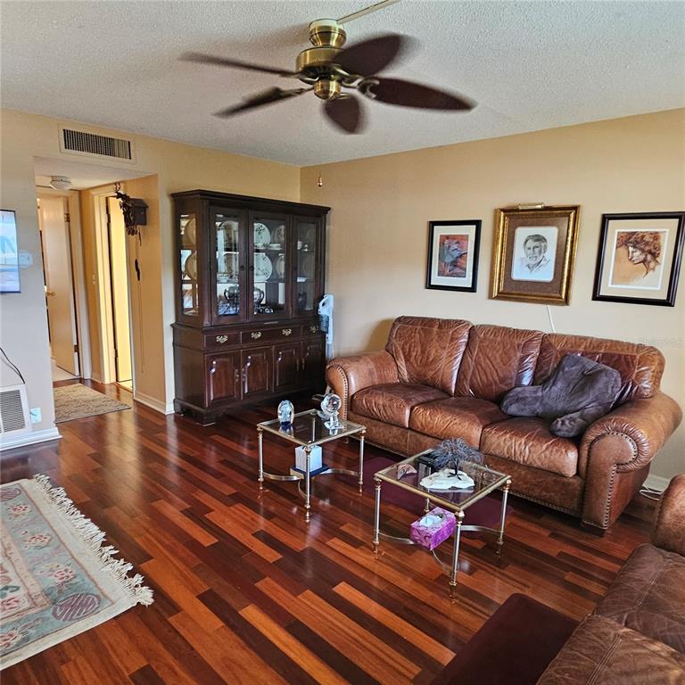 A living room features a brown leather sofa, wood flooring, and a dark wood china cabinet — 802 BRANDY WINE DRIVE, LARGO, FL