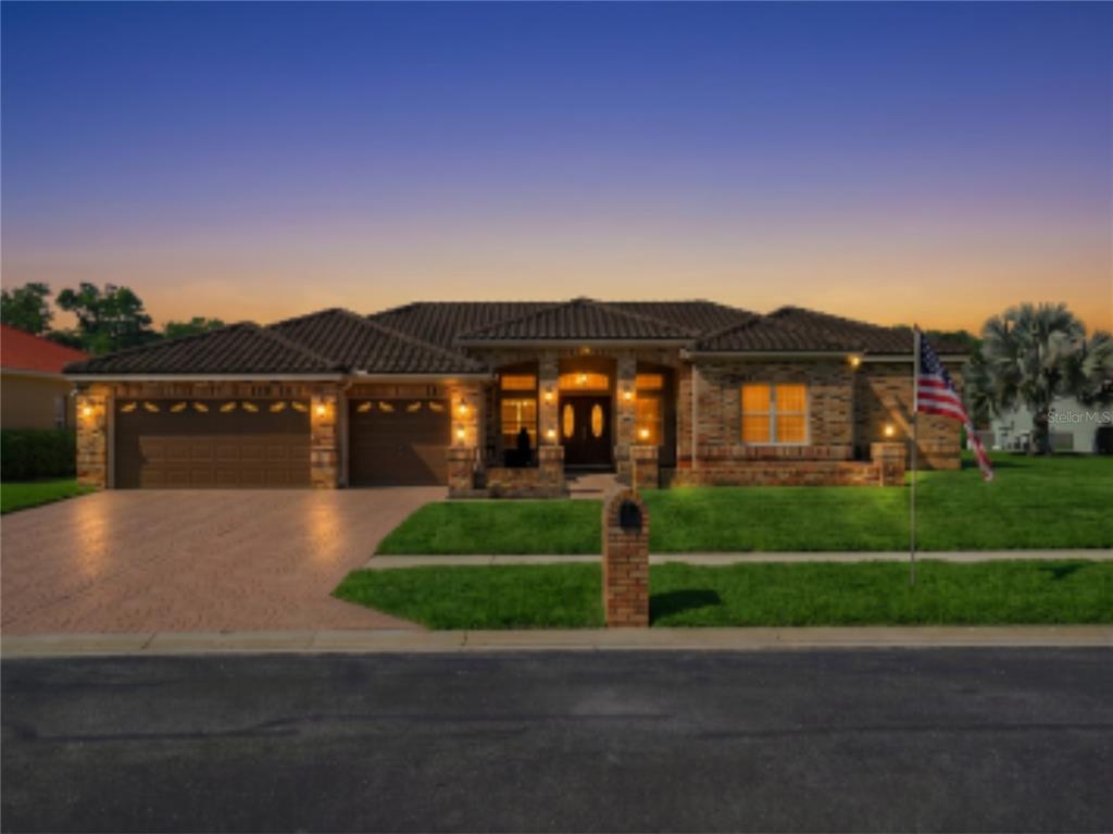 A single-story brick house with a two-car garage and a paved driveway at dusk — 3166 STERLING STREET, TARPON SPRINGS, FL