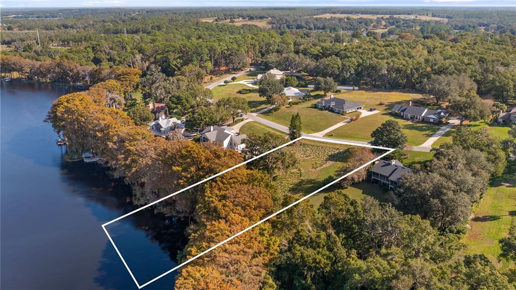 An aerial view shows a vacant waterfront lot outlined in white next to a house — LAKE SWATARA DRIVE, EUSTIS, FL