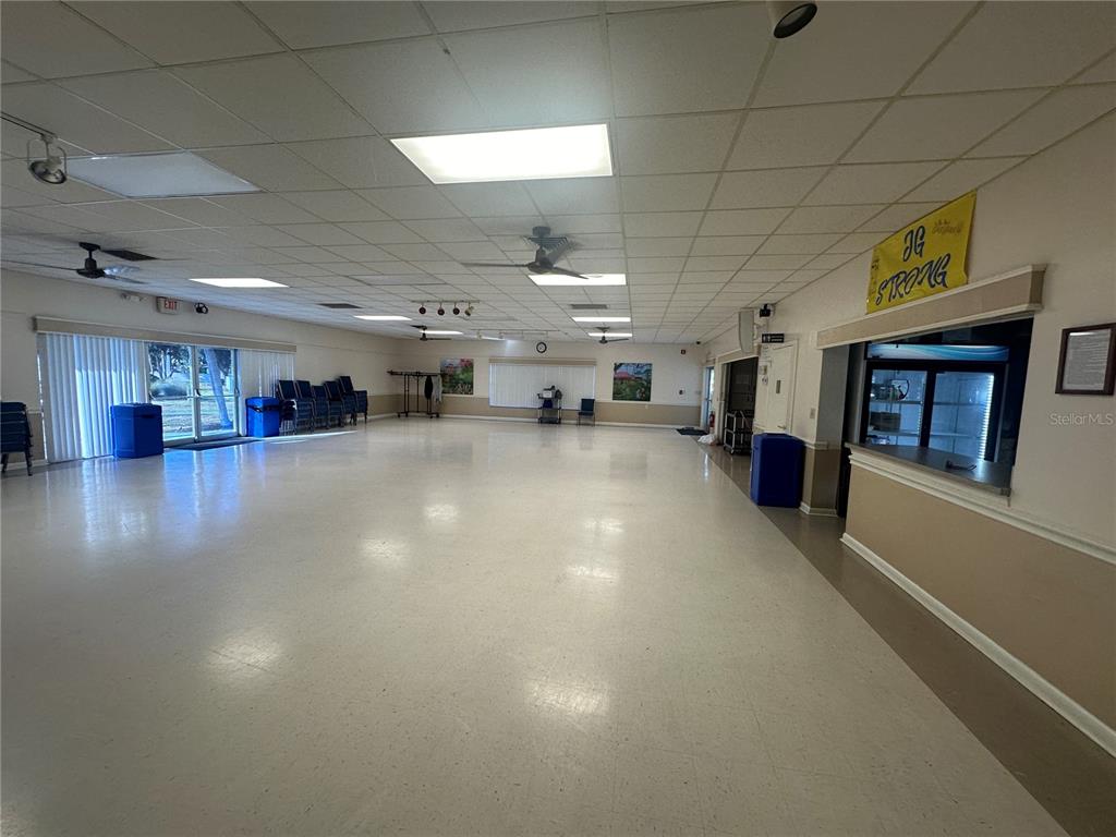 A large, open community room features white tile flooring, drop ceilings, and a service counter — 5881 SUNFLOWER ROAD, VENICE, FL