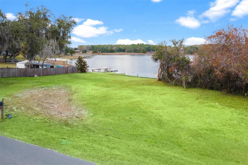A grassy, sloped backyard leads down to a lake with a wooden dock — 0 WILSON PARRISH ROAD, UMATILLA, FL