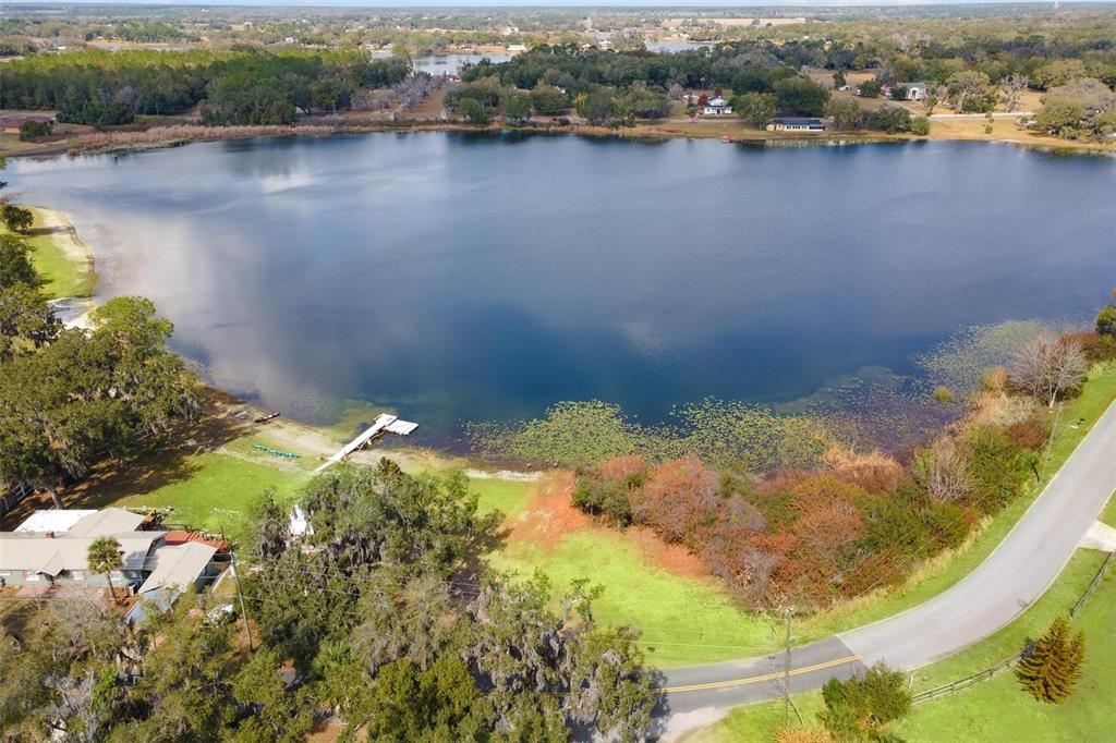An aerial view shows a lakefront property with a house, a dock, and a road — 0 WILSON PARRISH ROAD, UMATILLA, FL