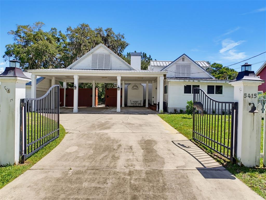 A white house with a large carport and open metal gates sits behind a driveway — 5415 RIVERSIDE DRIVE, YANKEETOWN, FL