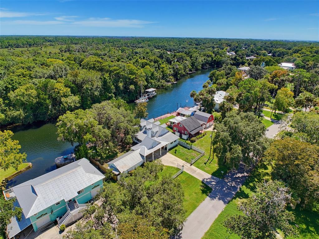 An aerial view shows several houses situated along a river surrounded by dense green trees — 5415 RIVERSIDE DRIVE, YANKEETOWN, FL