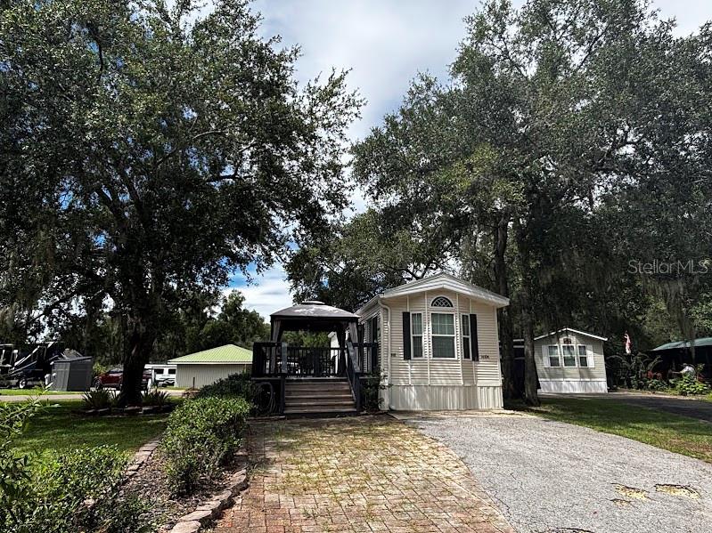 A manufactured home features a brick driveway, a covered gazebo, and mature trees — 14104 253RD AVENUE ROAD NE UNIT 398, FORT MC COY, FL