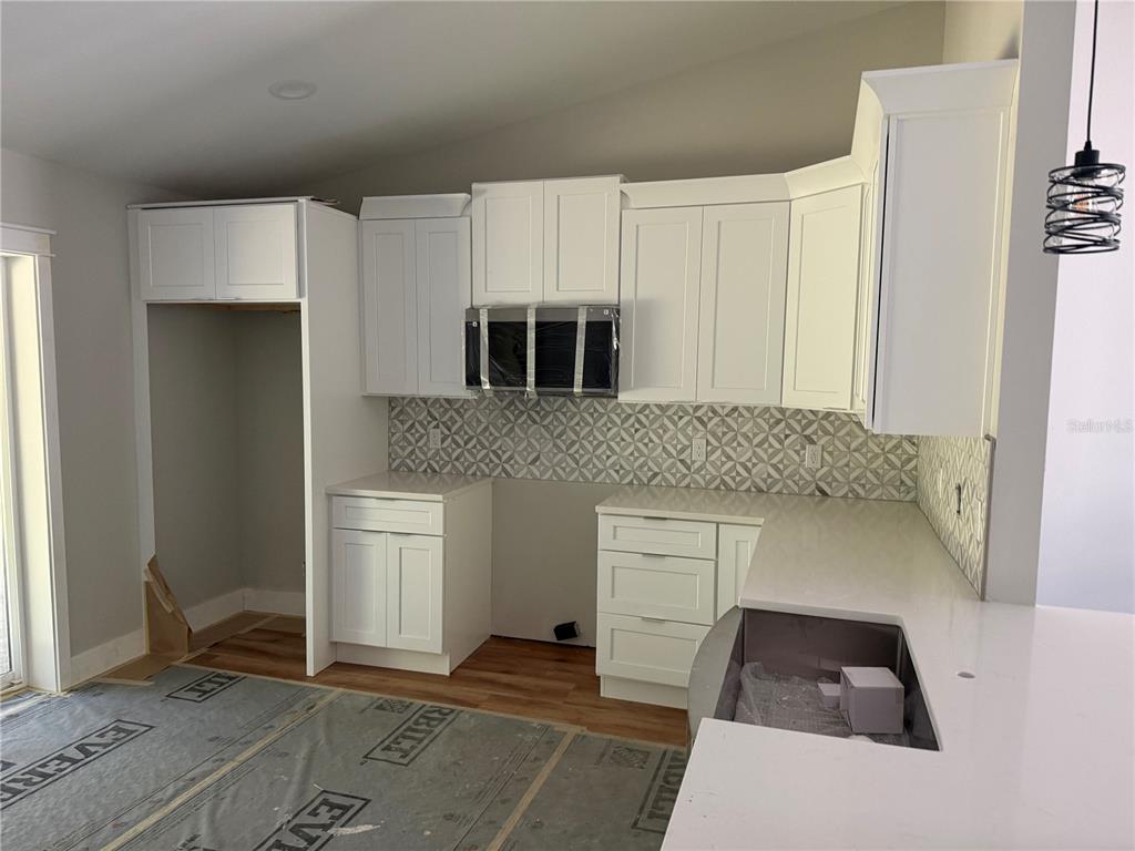 A kitchen under construction features white cabinets, a patterned backsplash, and a quartz countertop — 62 EMERSON DRIVE, PALM COAST, FL