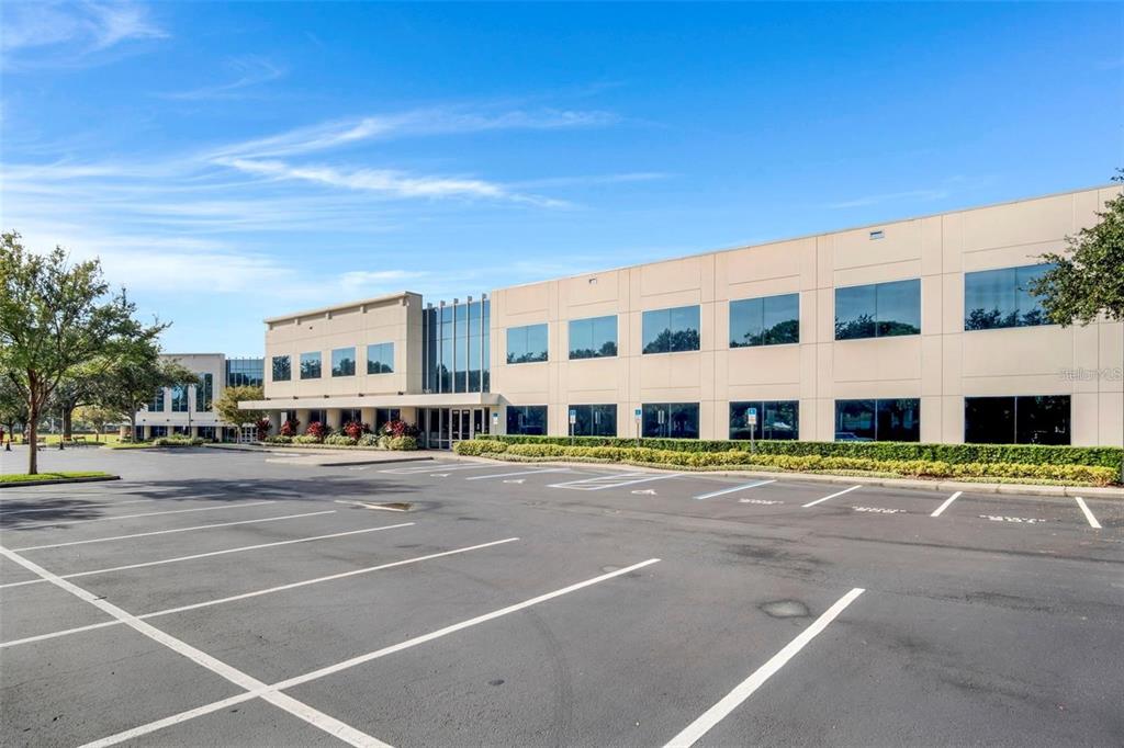 A multi-story commercial office building with a large asphalt parking lot in the foreground — 6200 METROWEST BOULEVARD UNIT 103D, ORLANDO, FL