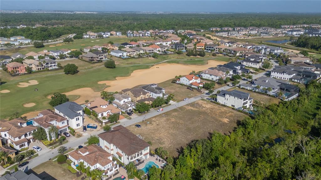 An aerial view shows a residential neighborhood with houses, a golf course, and vacant lots — 564 MUIRFIELD LOOP, REUNION, FL