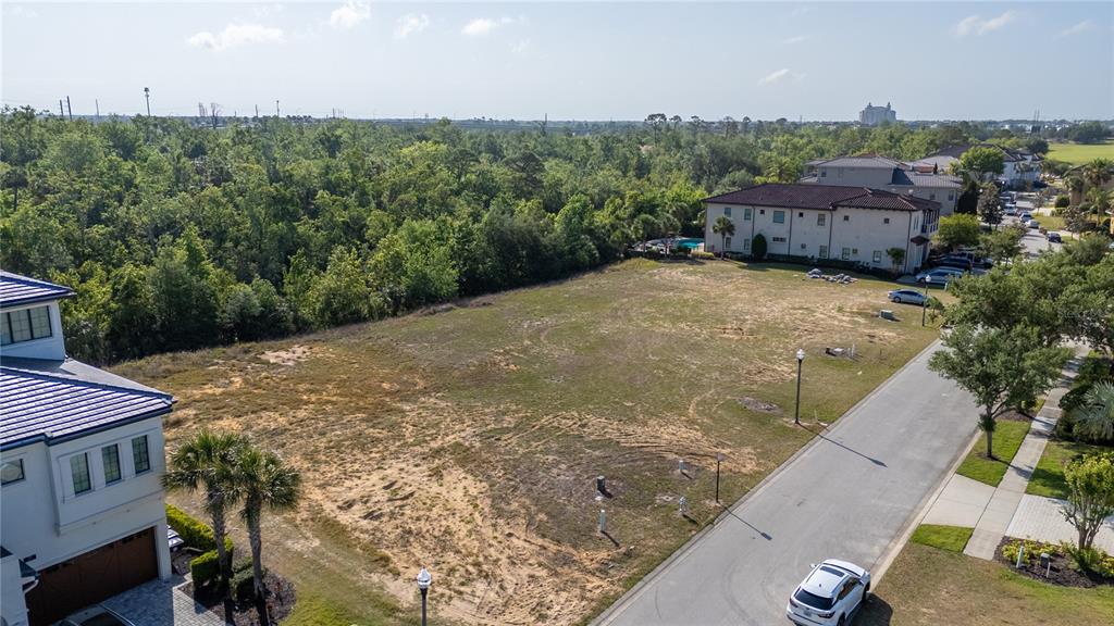 An aerial view shows a vacant residential lot situated between two large houses and trees — 564 MUIRFIELD LOOP, REUNION, FL