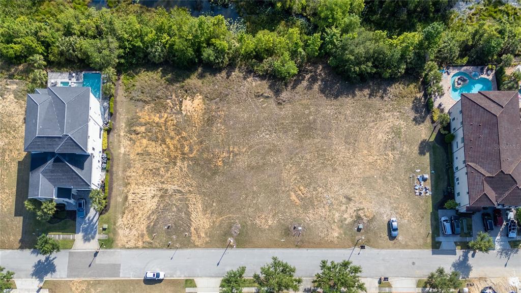 An aerial view shows a vacant residential lot situated between two large houses — 564 MUIRFIELD LOOP, REUNION, FL