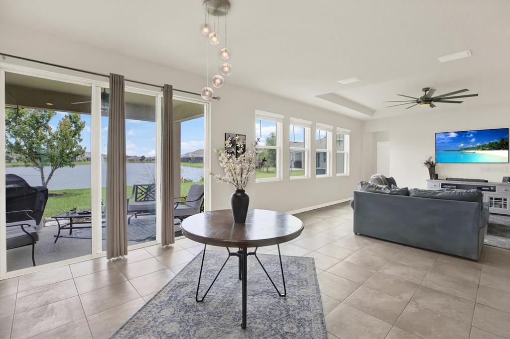 A living room with tile floors, a round dining table, and sliding doors to a lake — 6723 DEVESTA LOOP, PALMETTO, FL