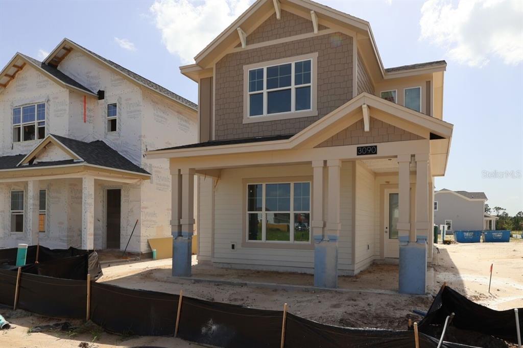 A two-story house under construction features tan siding, a front porch, and a shingled roof — 3090 BONFIRE PATH, ST CLOUD, FL