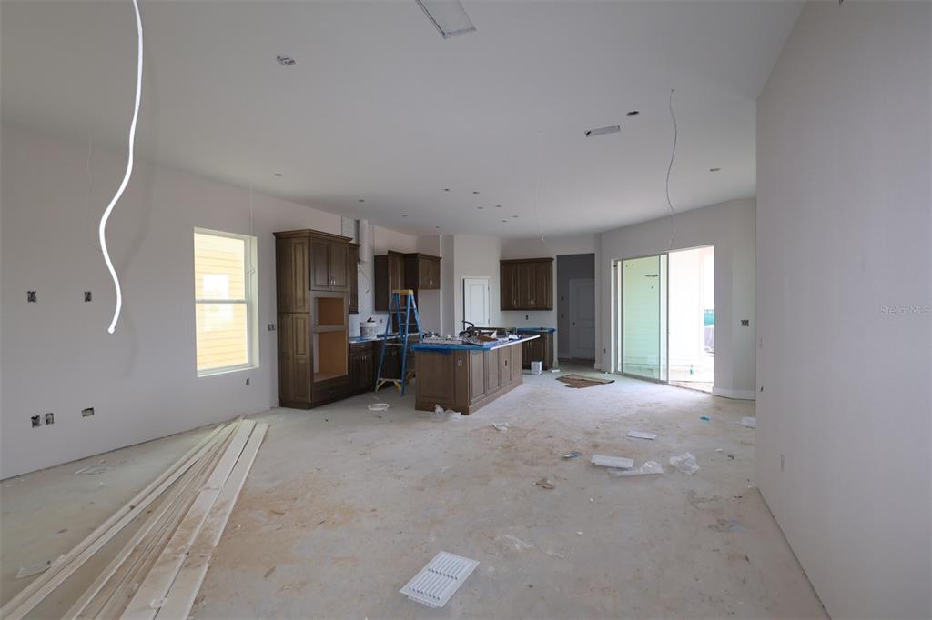 An unfinished kitchen features dark wood cabinetry, a center island, and bare concrete flooring — 3090 BONFIRE PATH, ST CLOUD, FL