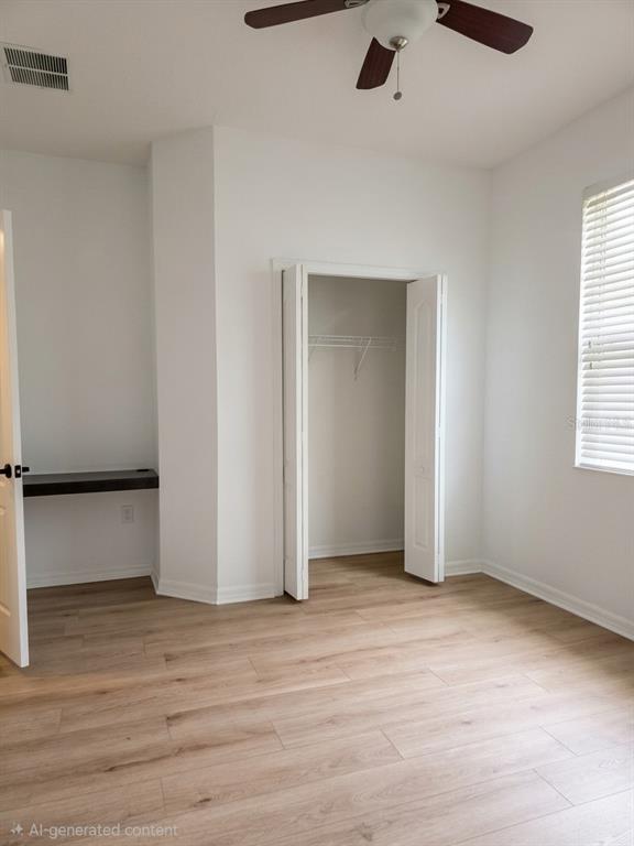 This room features light wood-look flooring, a ceiling fan, a built-in desk, and a closet — 3998 PACENTE LOOP, WESLEY CHAPEL, FL