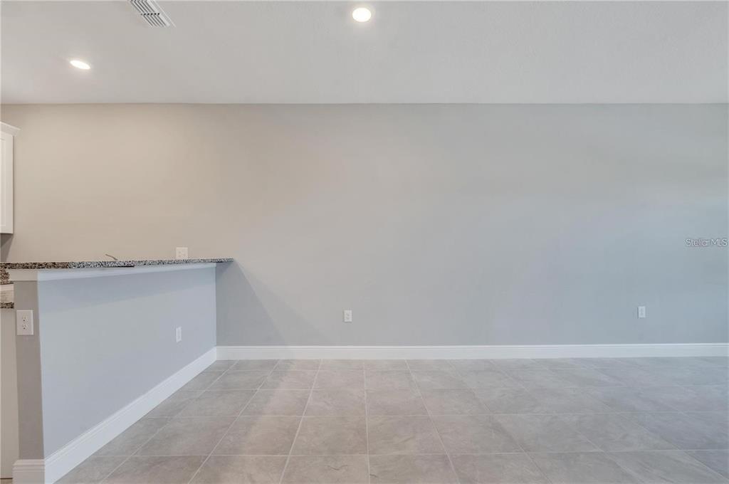 A kitchen breakfast bar with granite countertops sits in a room with gray tiled flooring — 1795 CORIANDER DRIVE UNIT 1795, POINCIANA, FL