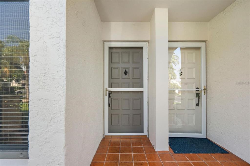 A covered entryway features two white storm doors with panel details and orange tiled flooring — 6277 BAHIA DEL MAR BOULEVARD UNIT 110, ST PETERSBURG, FL