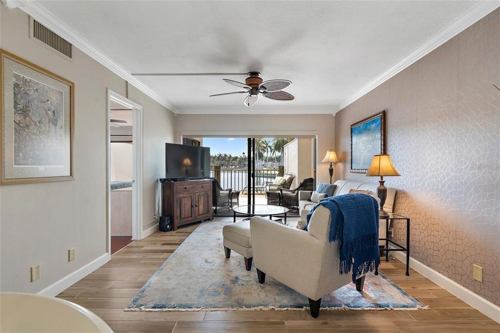 A living room features wood-look tile floors, a ceiling fan, and a sliding door to a balcony — 6277 BAHIA DEL MAR BOULEVARD UNIT 110, ST PETERSBURG, FL