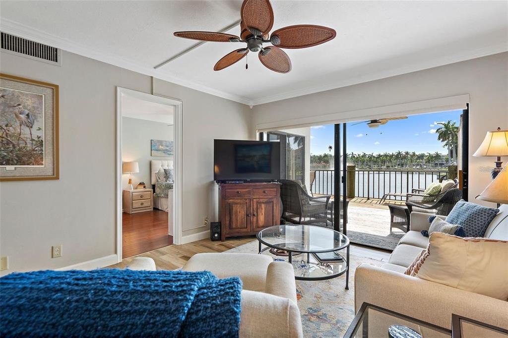 A living room features a ceiling fan, a television on a cabinet, and a balcony view — 6277 BAHIA DEL MAR BOULEVARD UNIT 110, ST PETERSBURG, FL