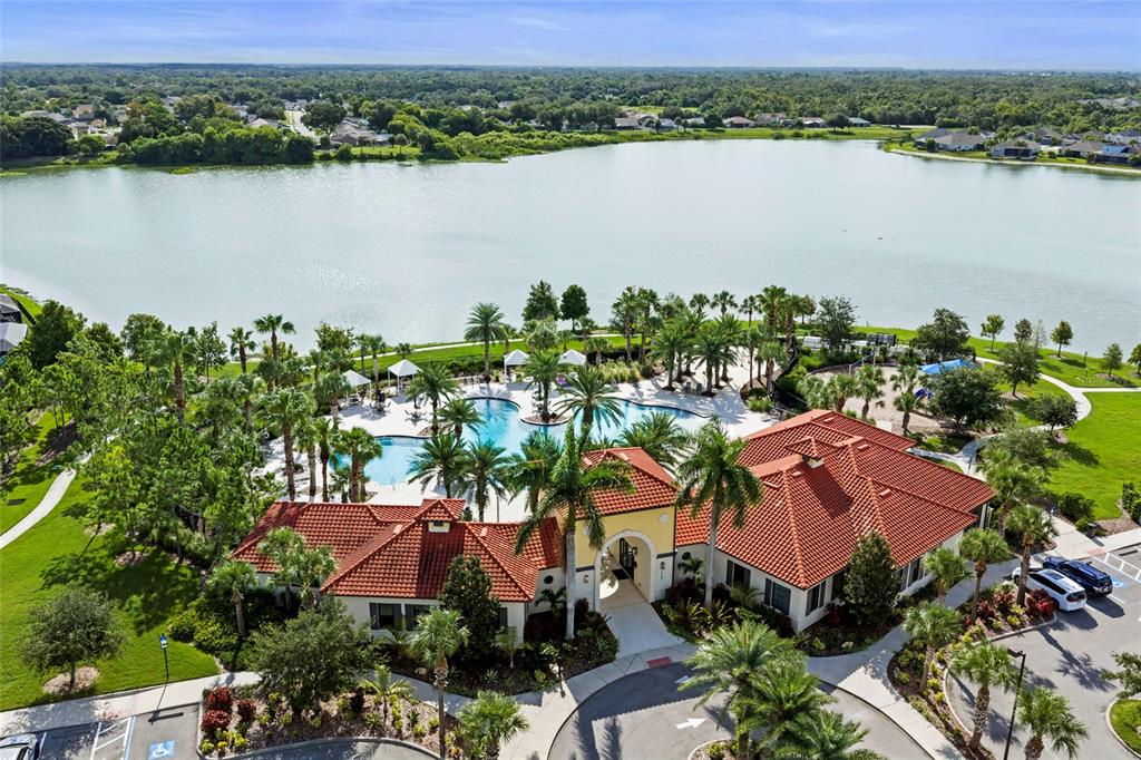 An aerial view shows a community clubhouse with a red-tiled roof next to a pool — 5540 PATANO LOOP, PALMETTO, FL