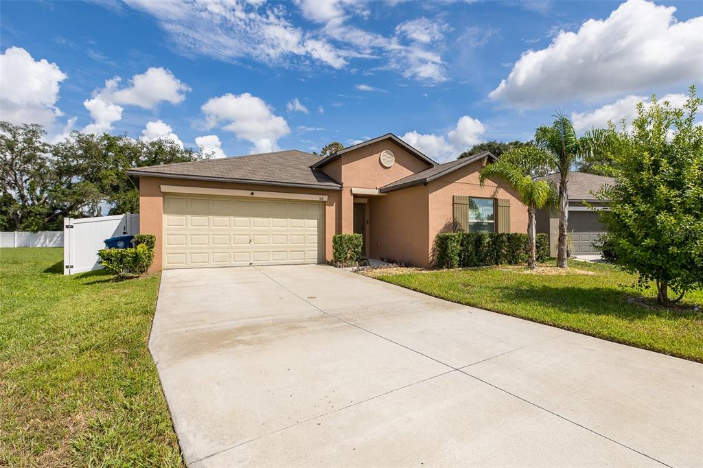 A single-story tan house with a two-car garage and a concrete driveway under a sky — 518 ARGYLL DRIVE, SPRING HILL, FL