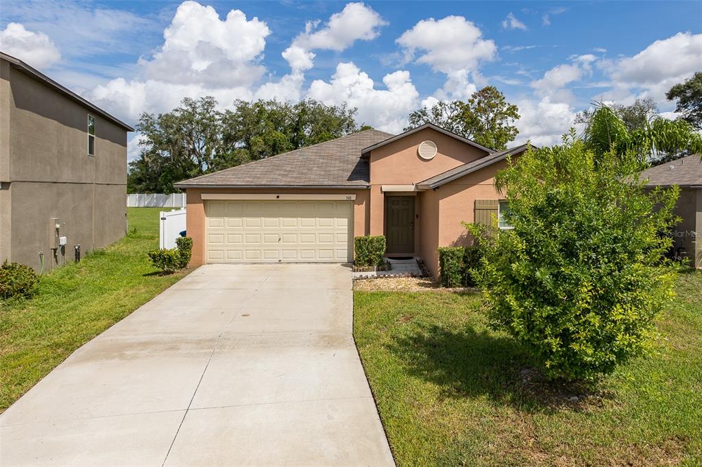 A single-story house with a beige stucco exterior, a two-car garage, and a concrete driveway — 518 ARGYLL DRIVE, SPRING HILL, FL