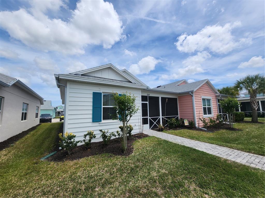 A white house with blue shutters and a pink section features a screened-in front porch — 218 OCEAN HAMMOCK LOOP, DAYTONA BEACH, FL
