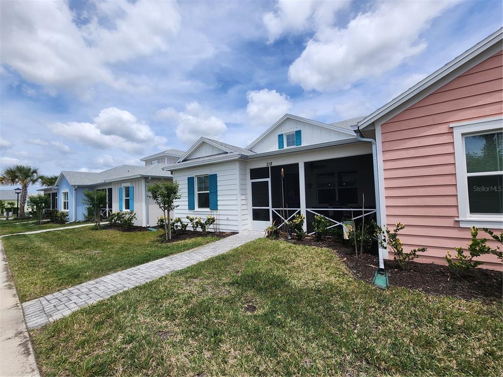 A row of colorful, single-story houses with screened-in front porches and paved walkways — 218 OCEAN HAMMOCK LOOP, DAYTONA BEACH, FL
