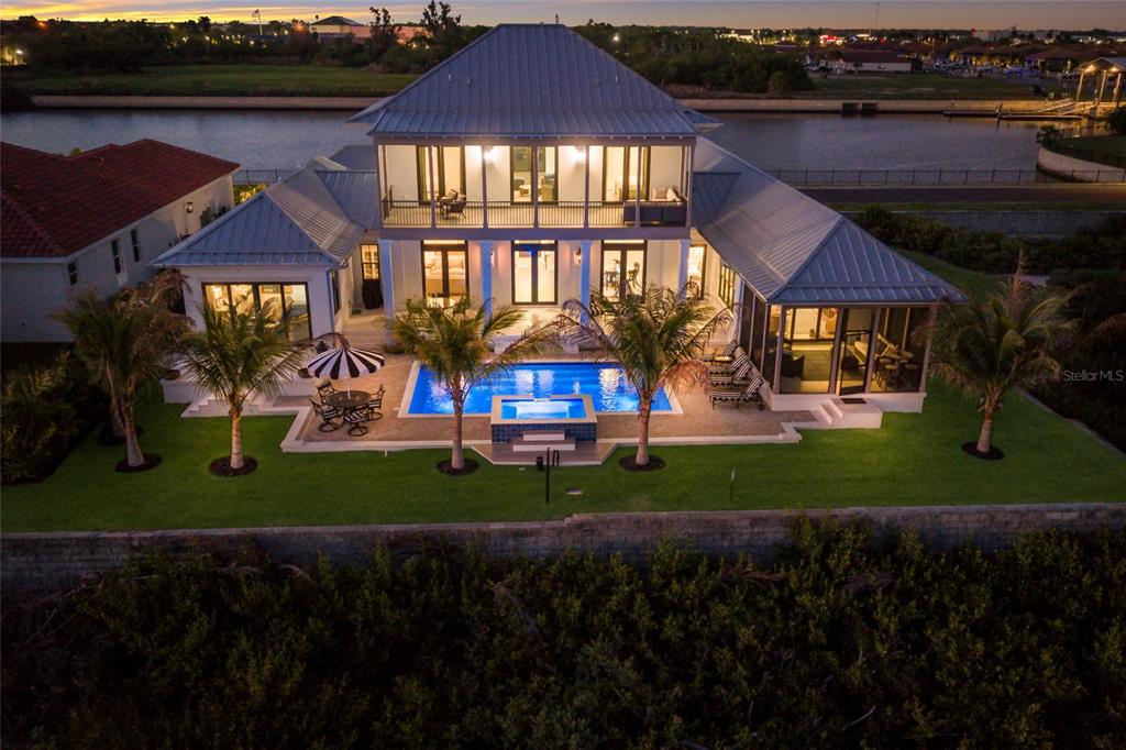 An aerial view of a waterfront house featuring a pool, spa, and metal roof — 1517 4TH STREET E, PALMETTO, FL