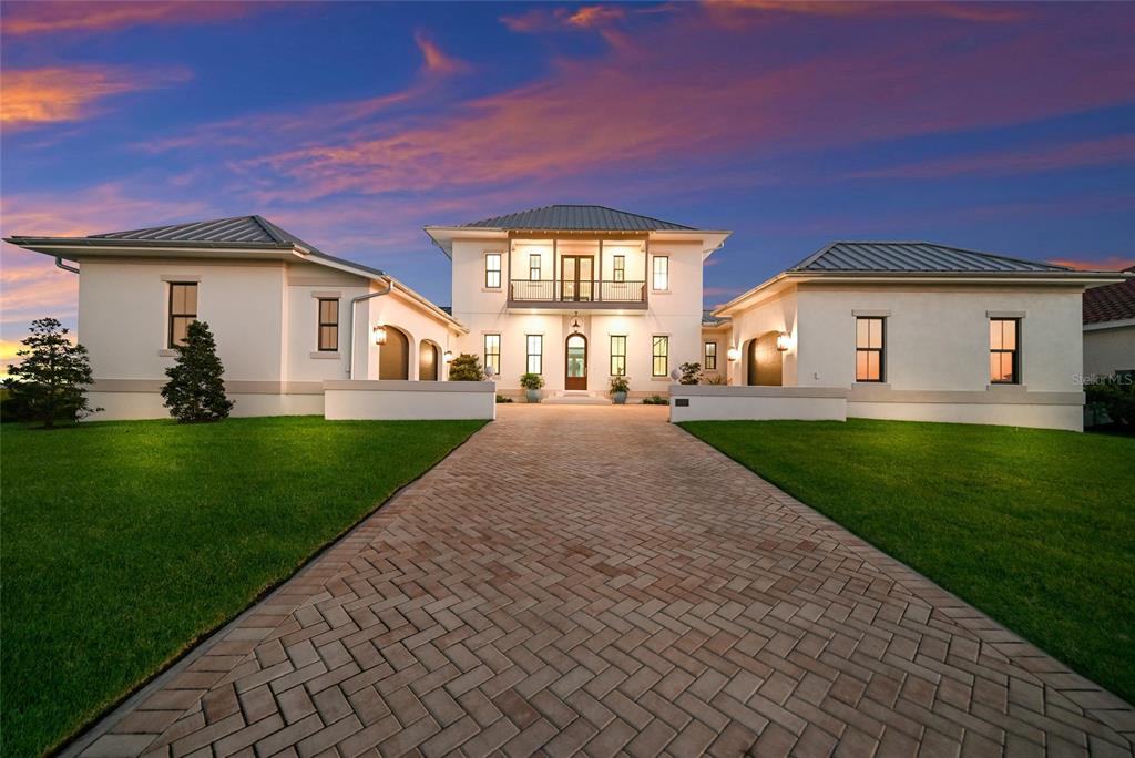 A large, two-story white house with a metal roof and a brick paver driveway — 1517 4TH STREET E, PALMETTO, FL
