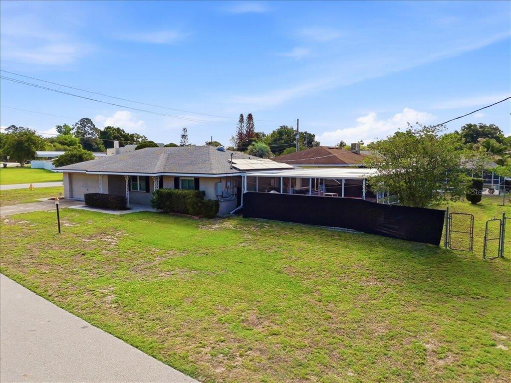 An exterior view of a single-story house with a screened-in patio and a fenced yard — 132 DUVAL ROAD, WINTER HAVEN, FL