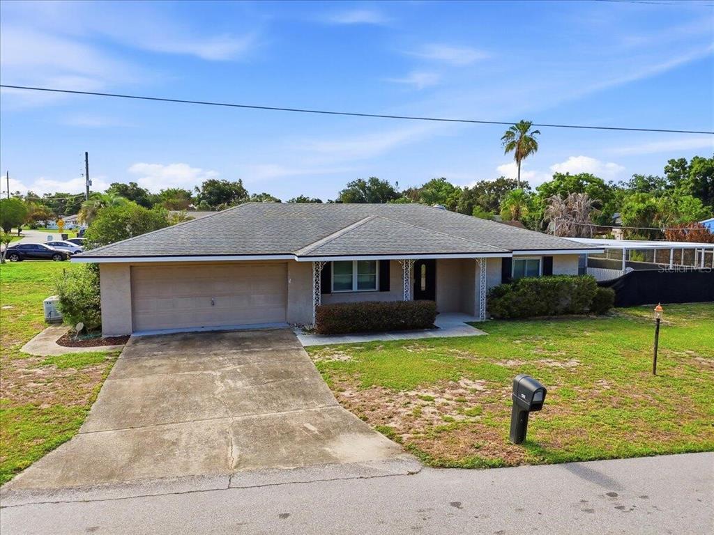 A single-story house with a beige exterior, a two-car garage, and a concrete driveway — 132 DUVAL ROAD, WINTER HAVEN, FL