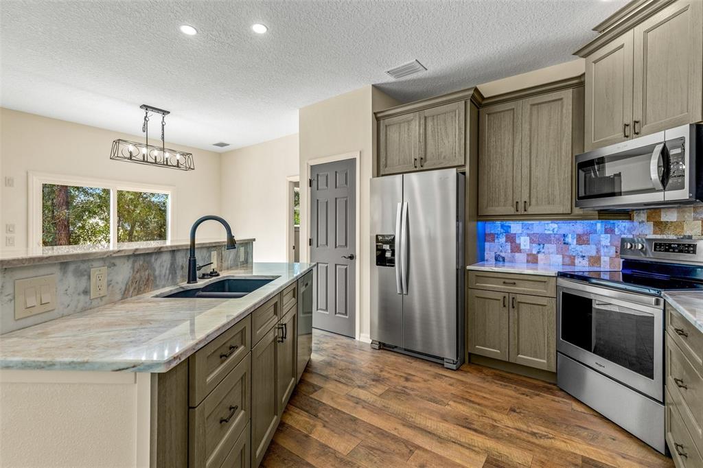 A kitchen features wood-toned cabinets, stainless steel appliances, a stone countertop, and a tile backsplash — 5332 W WESTCHASE LOOP, LECANTO, FL