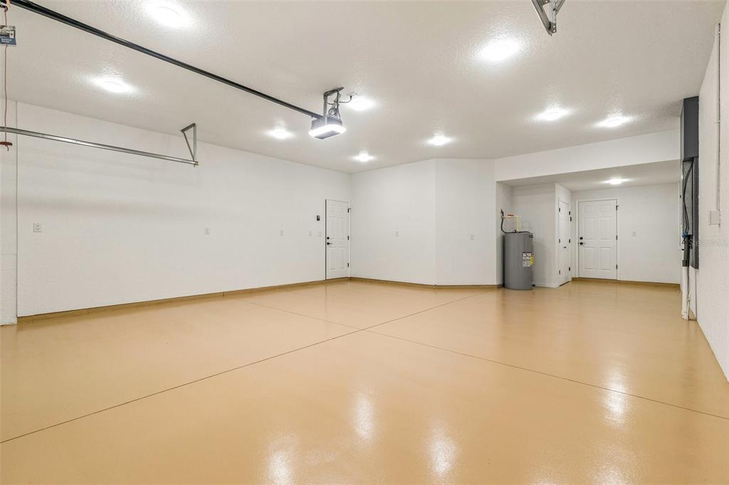 A spacious, empty garage with white walls, recessed lighting, and a smooth, tan-colored epoxy floor — 5332 W WESTCHASE LOOP, LECANTO, FL
