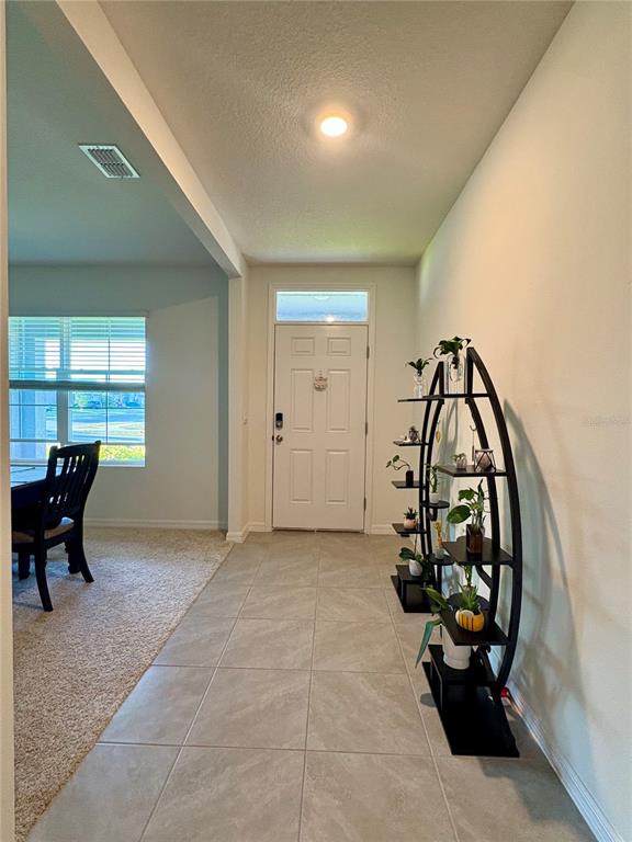 An entryway features light tile flooring, a white front door, and a curved display shelf — 3019 STATEN DRIVE, DELTONA, FL