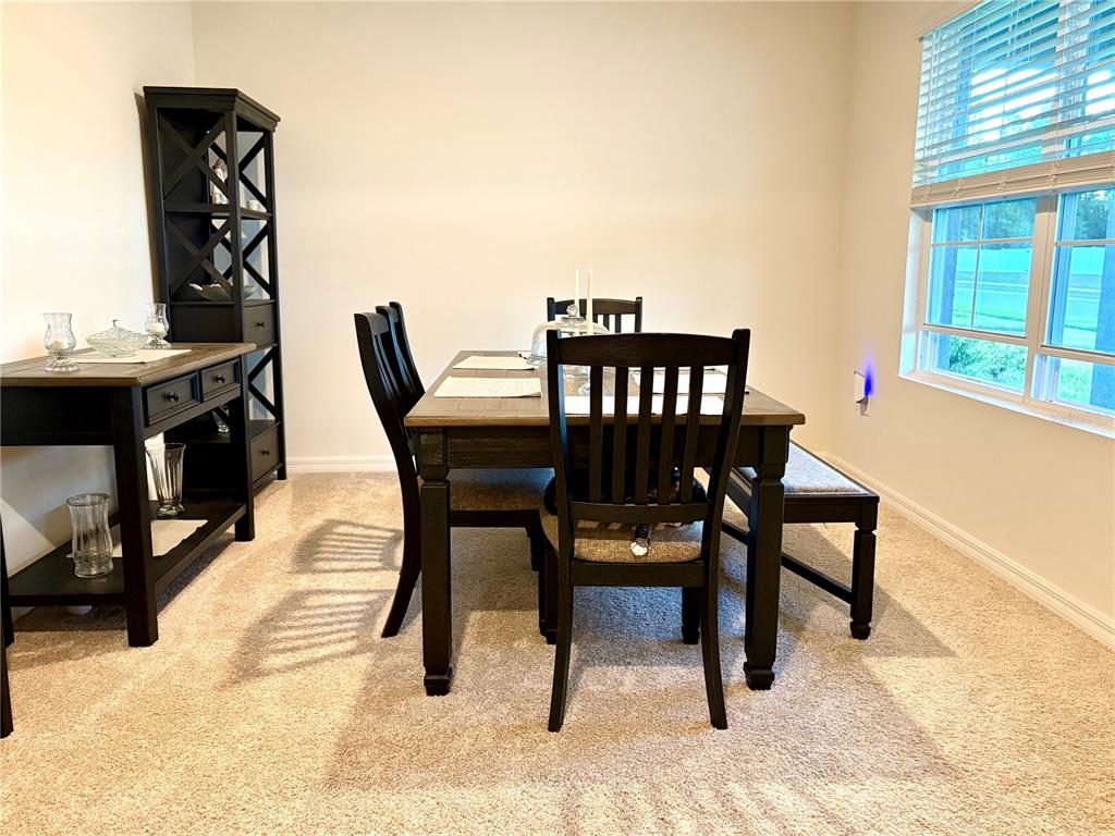 A dining room features a dark wood table, chairs, a bench, and a tall shelving unit — 3019 STATEN DRIVE, DELTONA, FL