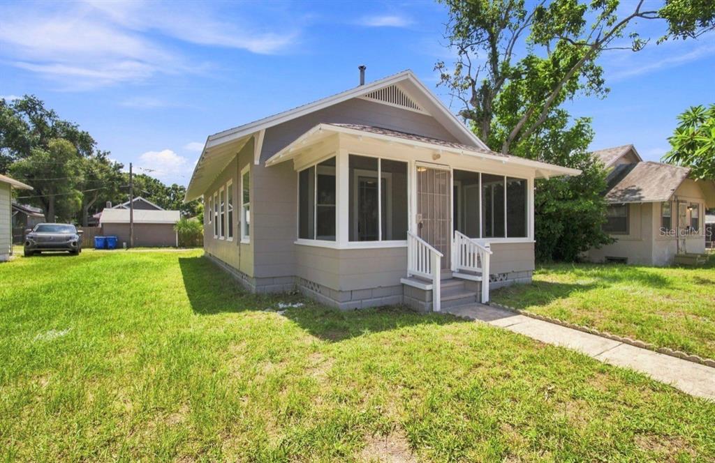 A kitchen with white cabinets, laminate countertops, stainless steel sink, and wood-look flooring — 1140 10TH AVENUE S, ST PETERSBURG, FL
