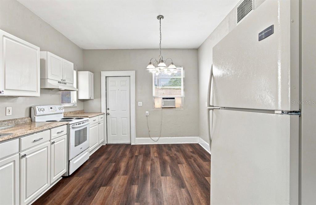 A kitchen with light gray walls, wood-look flooring, a white refrigerator, and a dining light — 1140 10TH AVENUE S, ST PETERSBURG, FL