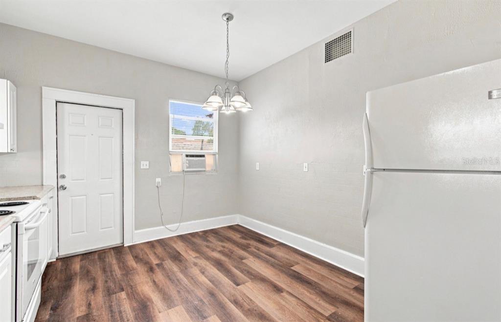 A kitchen features white cabinets, a white refrigerator, a chandelier, and wood-look flooring — 1140 10TH AVENUE S, ST PETERSBURG, FL