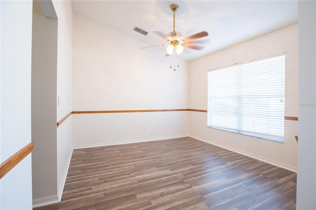 An empty room with wood-look flooring, white walls, a chair rail, and a ceiling fan — 534 TIMBER RUN LANE, GROVELAND, FL