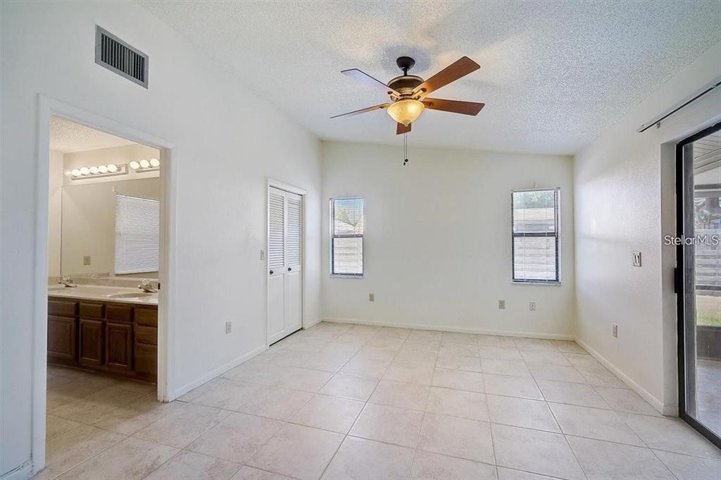 A bright room with white walls, tiled floors, a ceiling fan, and an attached bathroom — 6483 JARVIS ROAD, SARASOTA, FL
