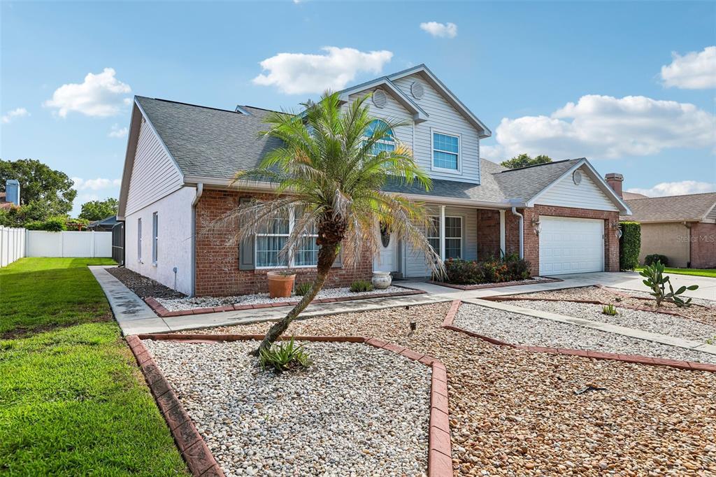 A two-story house with a brick and siding exterior, a palm tree, and gravel landscaping — 1424 DUMONT DRIVE, VALRICO, FL