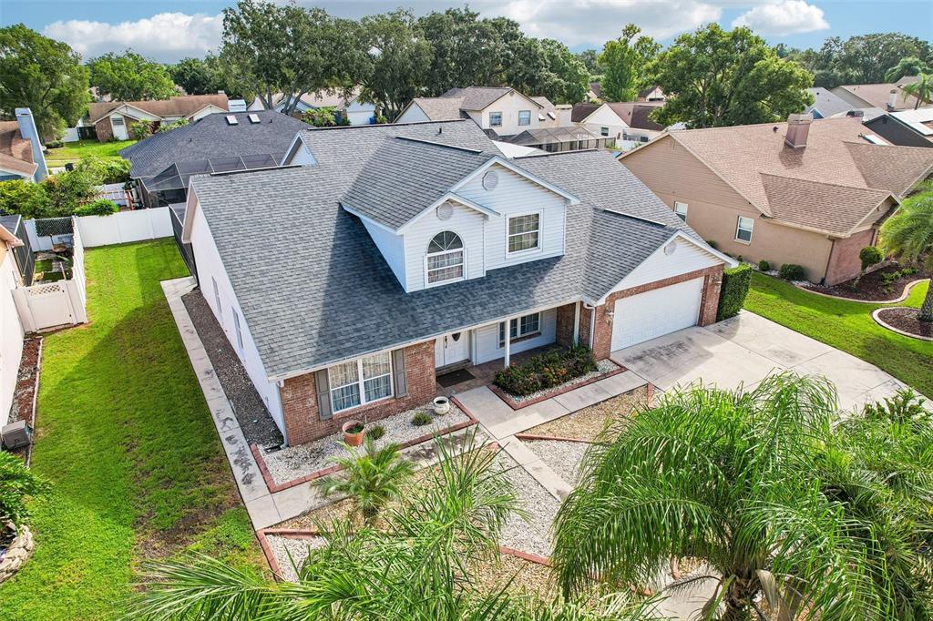 An aerial view of a two-story house with a brick facade, shingled roof, and driveway — 1424 DUMONT DRIVE, VALRICO, FL