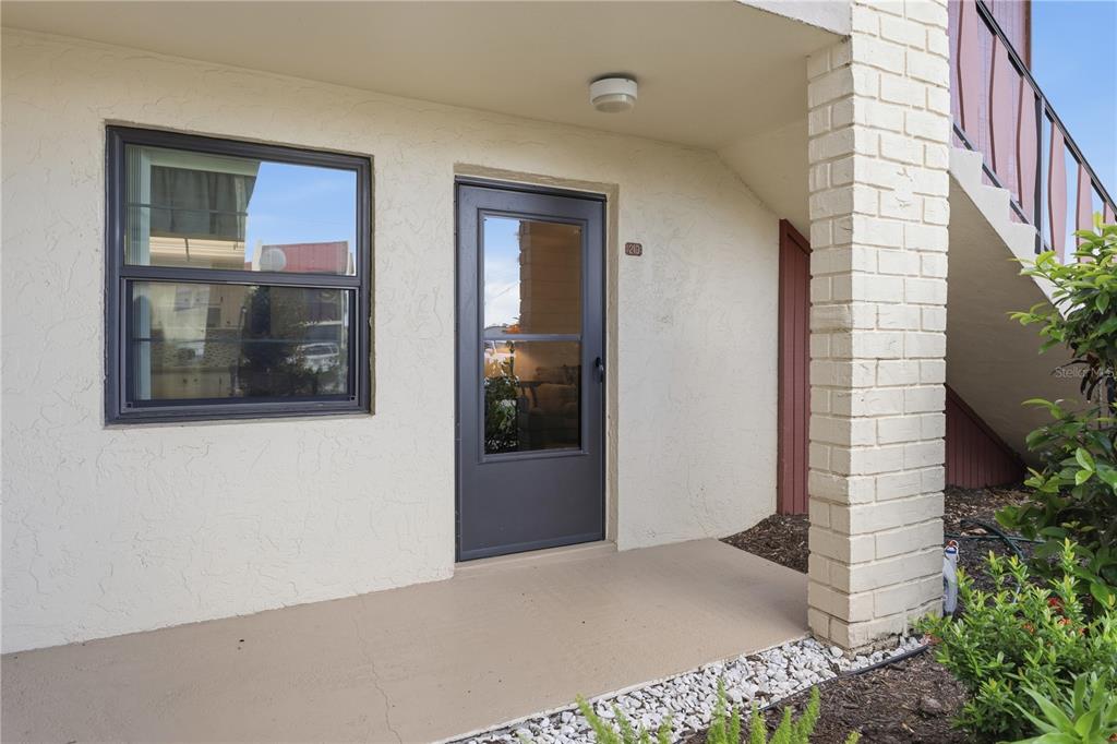 An exterior view of a building entrance with a glass storm door and a window — 72 BOUNDARY BOULEVARD UNIT 210, ROTONDA WEST, FL