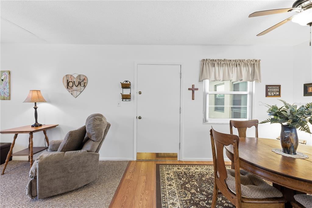 A living and dining area features a recliner, wooden table, and a white entry door — 72 BOUNDARY BOULEVARD UNIT 210, ROTONDA WEST, FL
