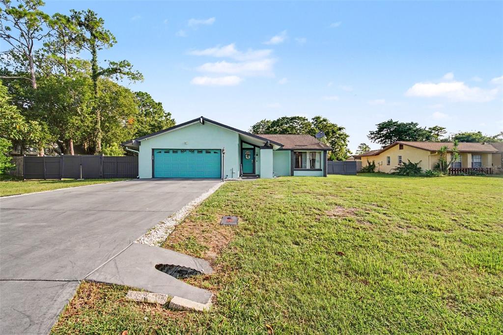 A light green single-story house with a teal garage door and a concrete driveway — 3 CLARK LANE, PALM COAST, FL